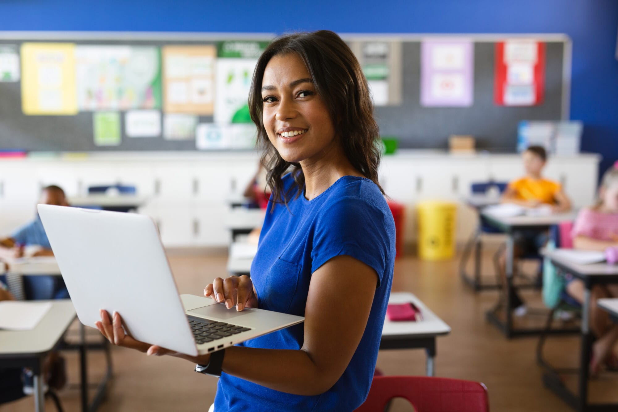 Portrait of african american female teacher holding laptop in th