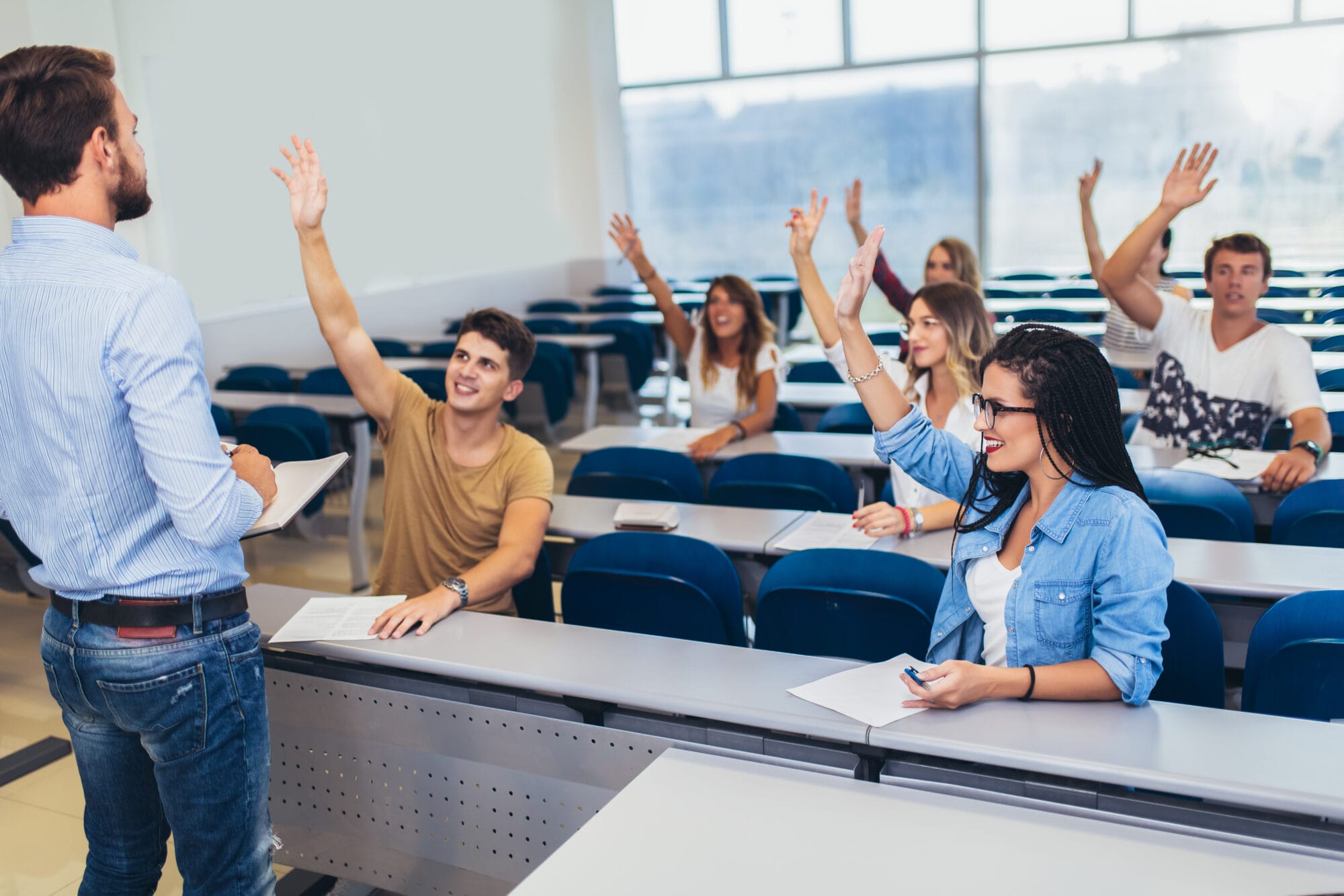 Group of students raising hands in class on lecture